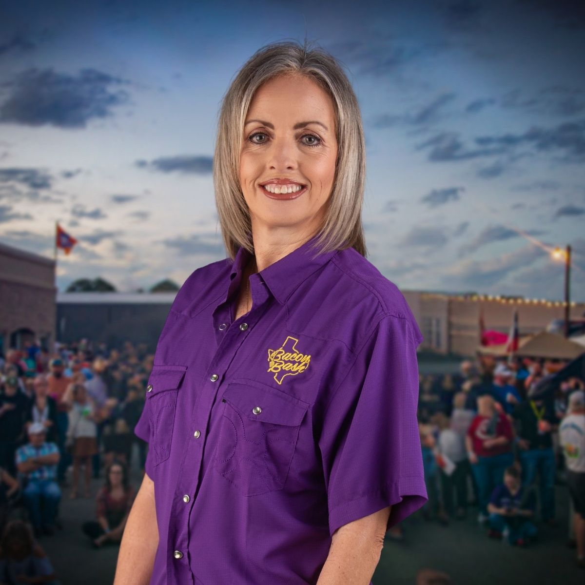 Christie Beyer, Board Member at Bacon Bash Texas with ABF Packing, smiling in a pink blouse at the lively festival gathering.